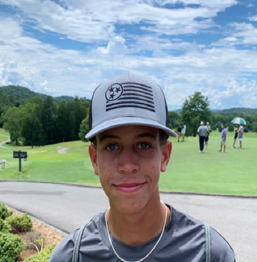 A man wearing a hat standing on top of a golf course.